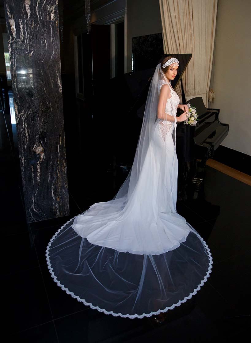 Model wearing white wedding dress and veil while holding bouquet